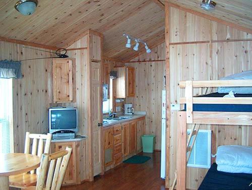 a wooden cabin with a kitchen and a bunk bed at Wilmington Camping Resort in Wilmington