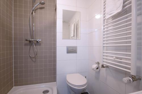 a white bathroom with a toilet and a shower at Amsterdam Canal Suites in Amsterdam