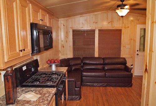 a living room with a leather couch in a tiny house at Bear Cave Camping Resort in Buchanan