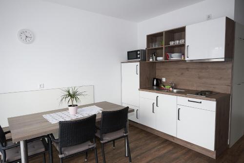 a kitchen with a table and chairs and a kitchen with white cabinets at L-Appartements in Burgau