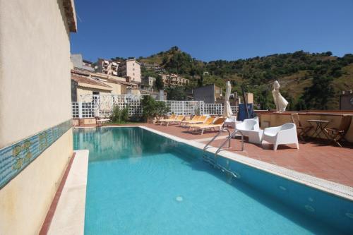 a swimming pool with chairs and a building at The Clock Houses Borgo Gallodoro in Letojanni