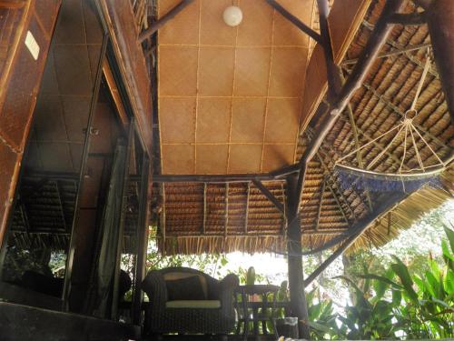 an outside view of a hut with a chair and trees at Fisherman's Hut , ขนำชาวเลโฮมสเตย์ in Pak Meng