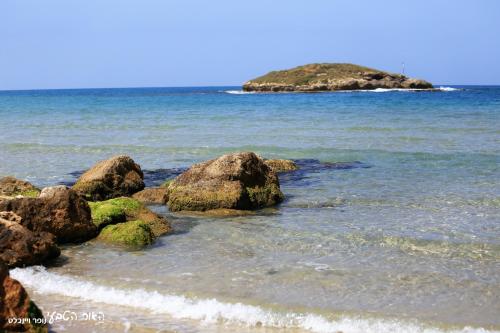 a beach with rocks and an island in the water at Dor Country Lodging in Dor