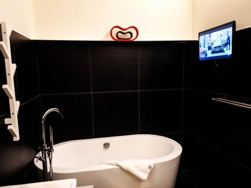 a bathroom with a bath tub and a tv on the wall at Bei Boutique Hotel in Muar