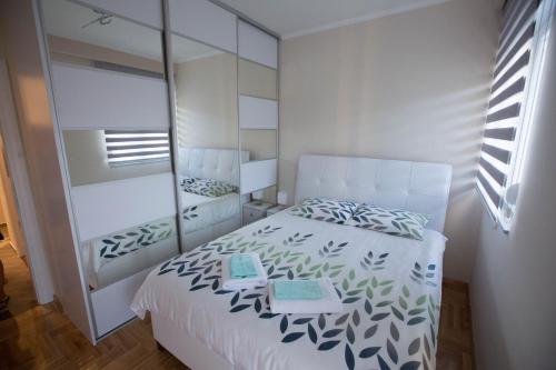 a bedroom with a white bed and a mirror at Apartman LUNA in Trebinje