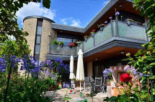ein Haus mit einer Terrasse mit Sonnenschirmen und Blumen in der Unterkunft Fewo Amber in Heimbach
