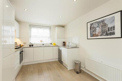 a white kitchen with a sink and a counter at Covent Garden Maisonette in London