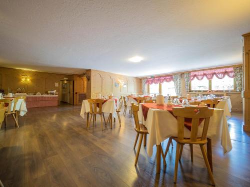 une salle à manger avec des tables et des chaises ainsi qu'une cuisine dans l'établissement Hotel Baita della Luna, à Livigno