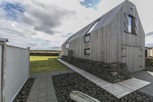 ein Holzhaus mit einer Steinmauer und einem Zaun in der Unterkunft Barn house by the sea in Stokkseyri