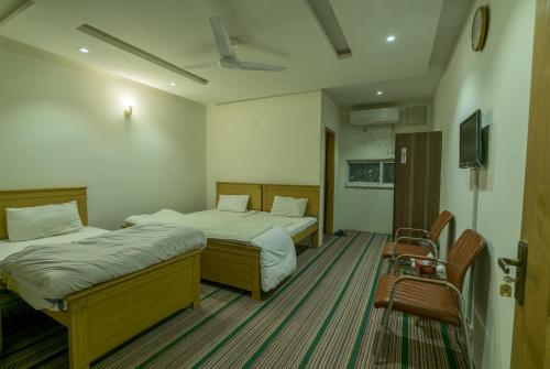 una habitación de hotel con 2 camas y una silla en BnB Hotel en Lahore