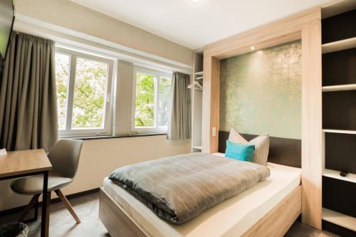 Schlafzimmer mit einem Bett, einem Schreibtisch und Fenstern in der Unterkunft Hotel DH -Deutsches Haus- in Emden