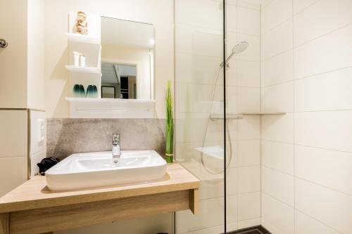 een badkamer met een wastafel en een douche bij Hotel DH -Deutsches Haus- in Emden