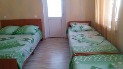 two beds in a small room with a window at Guest House on Abazgaa 30 in Gagra
