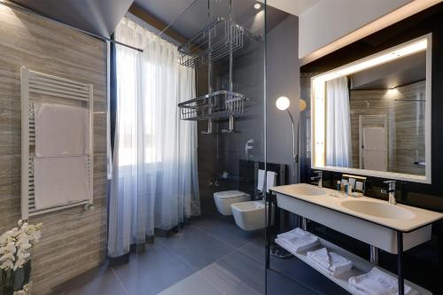 un bagno con lavandino, water e specchio di Stendhal Luxury Suites a Roma