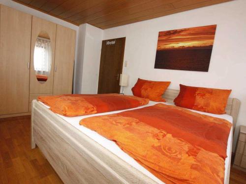a bedroom with a large bed with orange sheets at Ferienwohnung Franz in Malterdingen