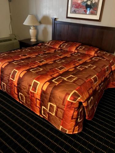 Una cama en una habitación de hotel con una manta. en Hub City Inn en Lubbock