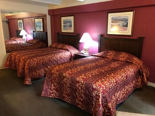 two beds in a hotel room with red walls at Hub City Inn in Lubbock