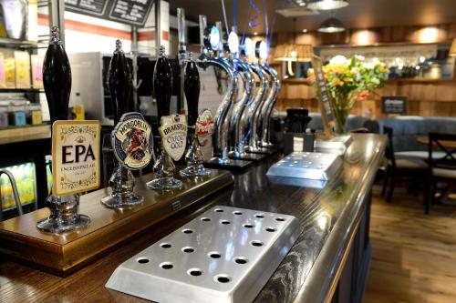 a bar with a bunch of wine glasses on a counter at Fallow Field, Telford by Marston's Inns in Telford