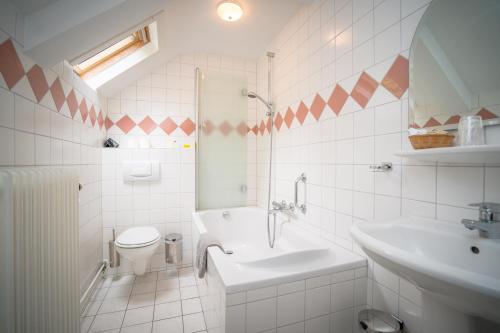 a white bathroom with a sink and a toilet at Herberg Restaurant 't Zwaantje in Mook