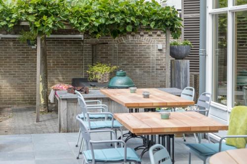 a patio with wooden tables and chairs and a grill at De Herberg Appartementen in Renesse