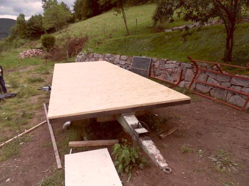 a wooden table sitting next to a stone wall at La roulotte du bucheron in Lapoutroie