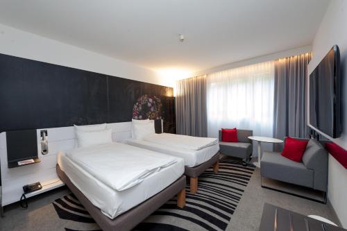 a hotel room with two beds and a tv at Novotel München City in Munich