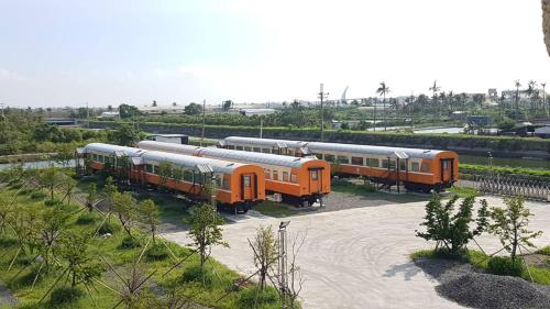 Trois trains oranges sont garés sur un parking dans l'établissement Da Yi Train Homestay, à Donggang