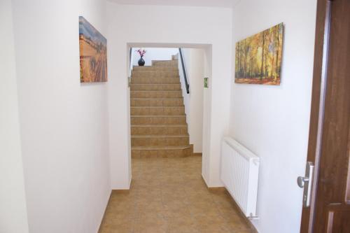 a hallway with stairs and paintings on the walls at Penzion Rozhovice in Rozhovice