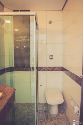 a bathroom with a toilet and a glass shower at Jardim Hotel in São Bernardo do Campo