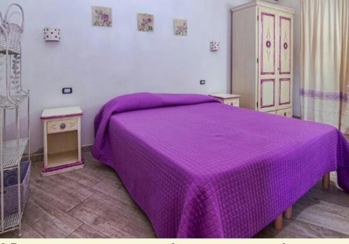 a bedroom with a purple bed with a purple blanket at Il Leccio in Tortolì