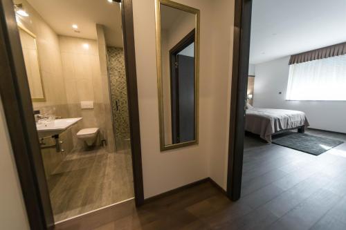 a bathroom with a mirror and a sink and a bed at Rooms The King's Pub in Kutina