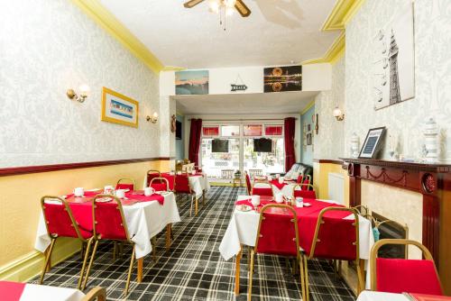 a restaurant with red tables and chairs in a room at Valdene Hotel in Blackpool