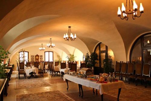 una grande sala da pranzo con tavoli, sedie e lampadari a braccio di Hotel Medieval a Alba Iulia