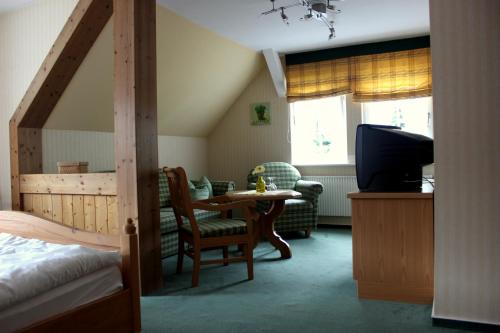 Schlafzimmer mit einem Bett, einem Tisch und einem TV in der Unterkunft Gasthof Zur Hohen Hunau in Schmallenberg