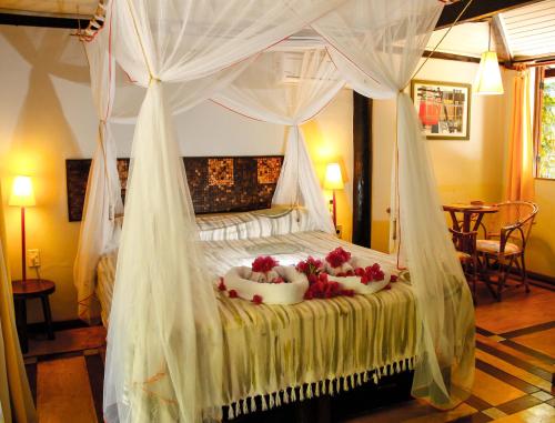 Un dormitorio con una cama con dosel y flores. en Vilangelim Eco-Pousada, en Imbassai