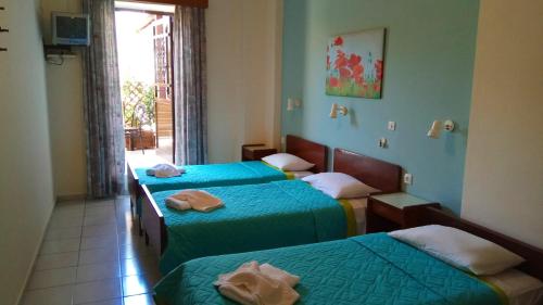 a hotel room with three beds and a window at Niki's Pension in Rhodes Town