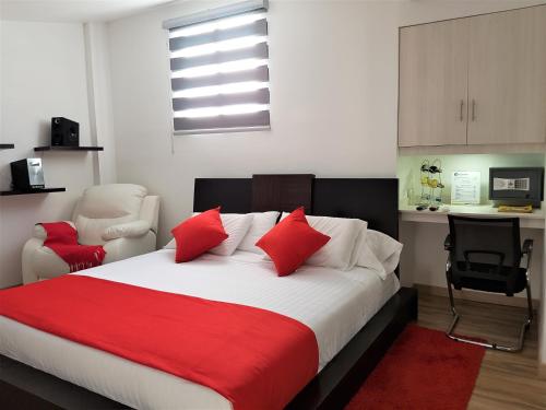 a bedroom with a large bed with red pillows at Hotel San Jeronimo Armenia in Armenia