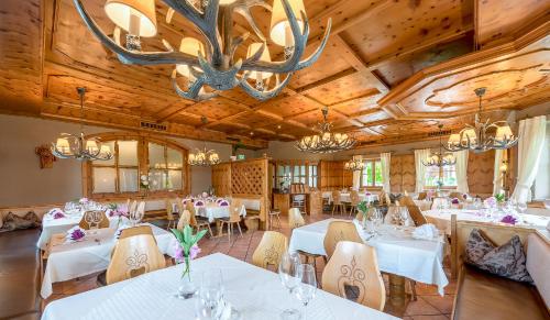 une salle à manger avec des tables et des chaises blanches et un lustre dans l'établissement Landhotel Drei Eichen, à Eugendorf