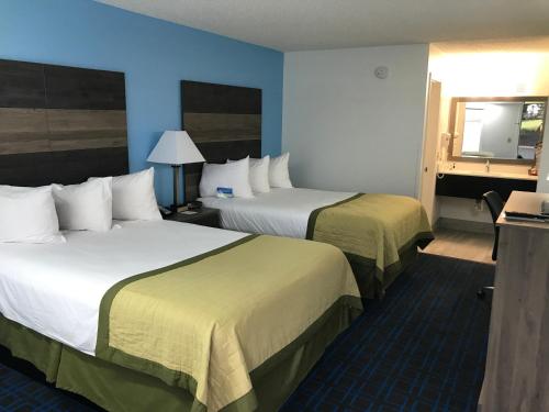a hotel room with two beds and a mirror at Baymont by Wyndham Anderson Clemson in Anderson