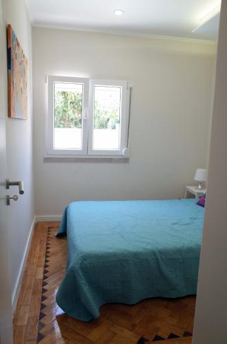a bedroom with a blue bed and two windows at Lisbon Beach Apartments 2 in Costa da Caparica
