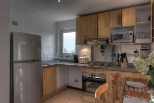 a kitchen with wooden cabinets and a stainless steel refrigerator at Pucón in Pucón