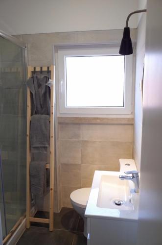 a bathroom with a toilet and a sink and a window at Lisbon Beach Apartments 4 in Costa da Caparica
