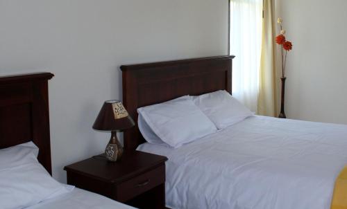 a bedroom with two beds and a lamp on a night stand at La Quinta San Andrés in Ibarra