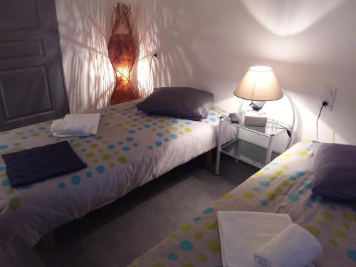 a bedroom with two beds and a lamp and a table at L'Orchidée in Lassay