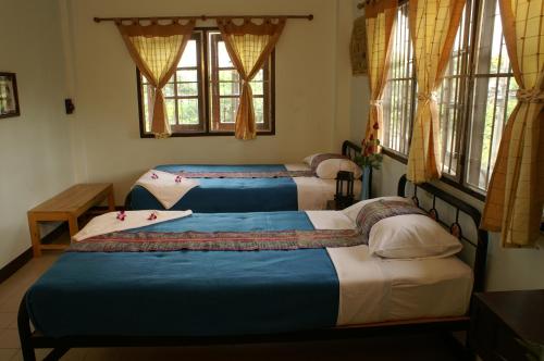 three beds in a room with windows at Trekker Camp in Chiang Mai