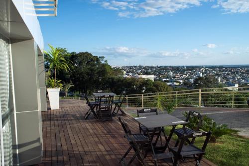 a patio with tables and chairs and a view of a city at AJ Hotel Chapecó - Fácil Acesso Pátio Shopping e Rótula da Bandeira in Chapecó