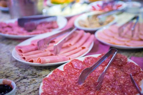 a table topped with plates of food with meat at AJ Hotel Chapecó - Fácil Acesso Pátio Shopping e Rótula da Bandeira in Chapecó