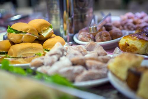 a table topped with plates of sandwiches and other foods at AJ Hotel Chapecó - Fácil Acesso Pátio Shopping e Rótula da Bandeira in Chapecó