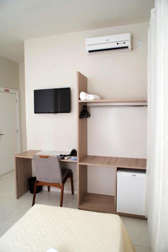 a room with a bed and a desk with a television at AJ Hotel Chapecó - Fácil Acesso Pátio Shopping e Rótula da Bandeira in Chapecó