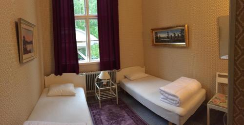 a small room with two beds and a window at Tivedens Hostel-Vandrarhem in Karlsborg